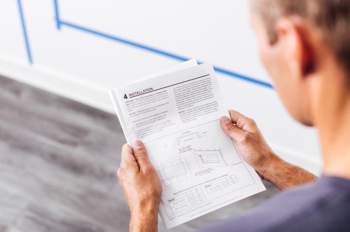 Homeowner reading installation guide in preparation for installing electric fireplace.