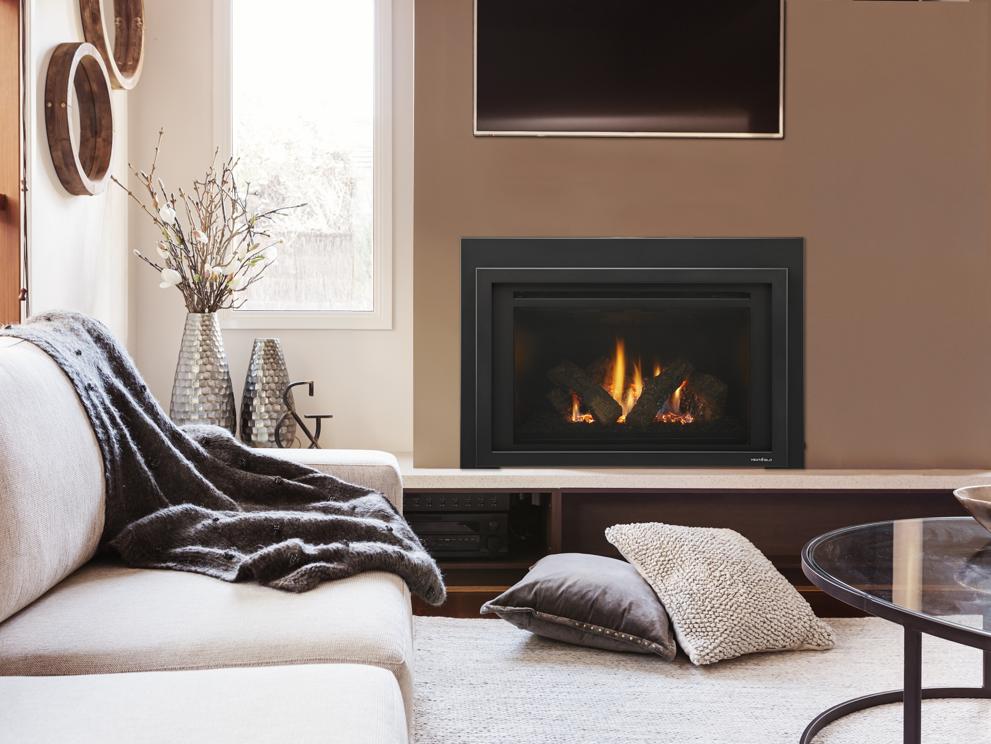 Transitional living room with gas fireplace insert in tan wall, couch with draped throw and pillows on floor.