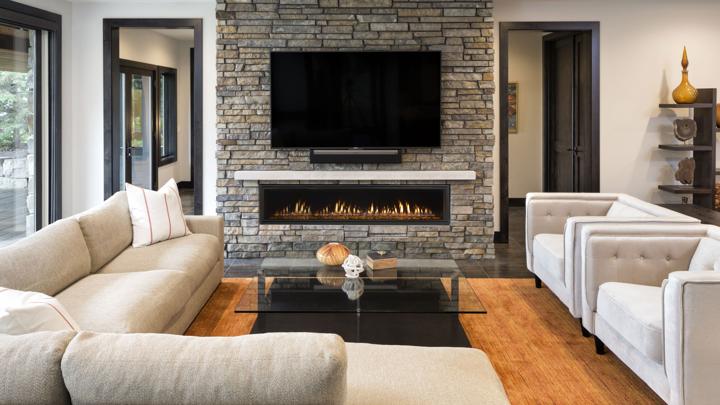 Heat & Glo Mezzo linear modern indoor gas fireplace with ribbon flame and amber glass in living room with TV above. 