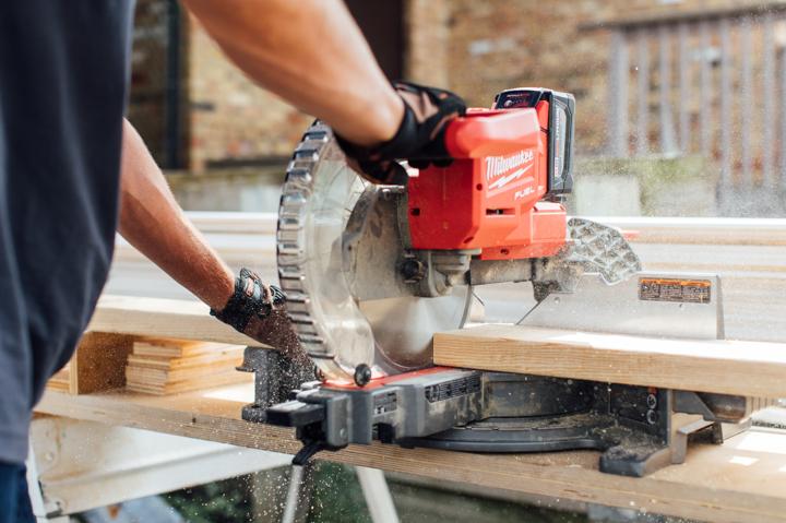 Homeowner using miter saw to cut framing pieces for installing electric fireplace.