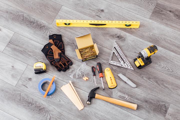 Tools assembled on floor needed for electric fireplace installation such as drill, level, hammer and tape measure.