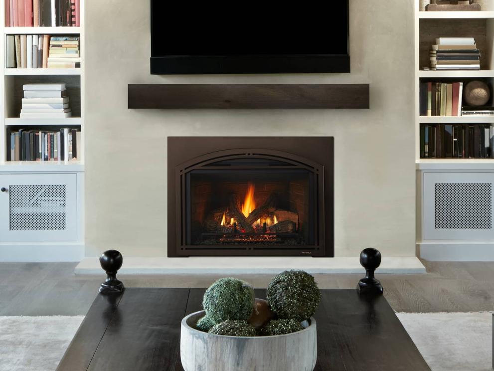 Gas fireplace insert in light gray hearth wall with TV overhead and book shelves on each side.